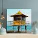 Highland Dunes A Yellow Life Guard Cabin On The Beach During Daytime - 1 Piece Square Graphic Art Print On Wrapped Canvas in Blue/Yellow | Wayfair