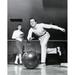 Young man bowling in a bowling alley with a young woman behind him Poster Print (18 x 24)