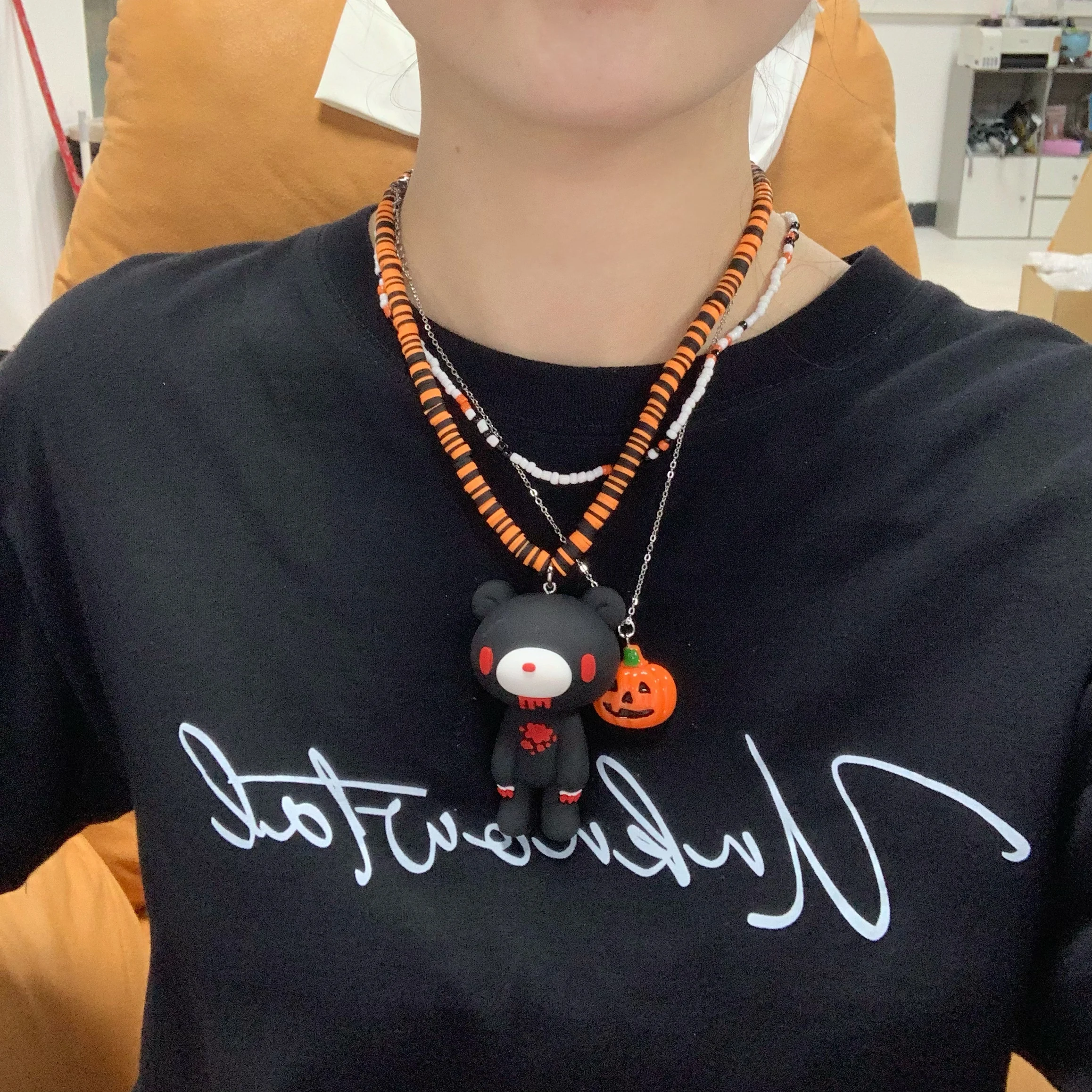 Halloween – inspirierte Halsketten: Bunte Perlenketten mit schwarzen Bären- und Kürbis-/Geisteranhängern. Gruselig – süßer Stil. Image