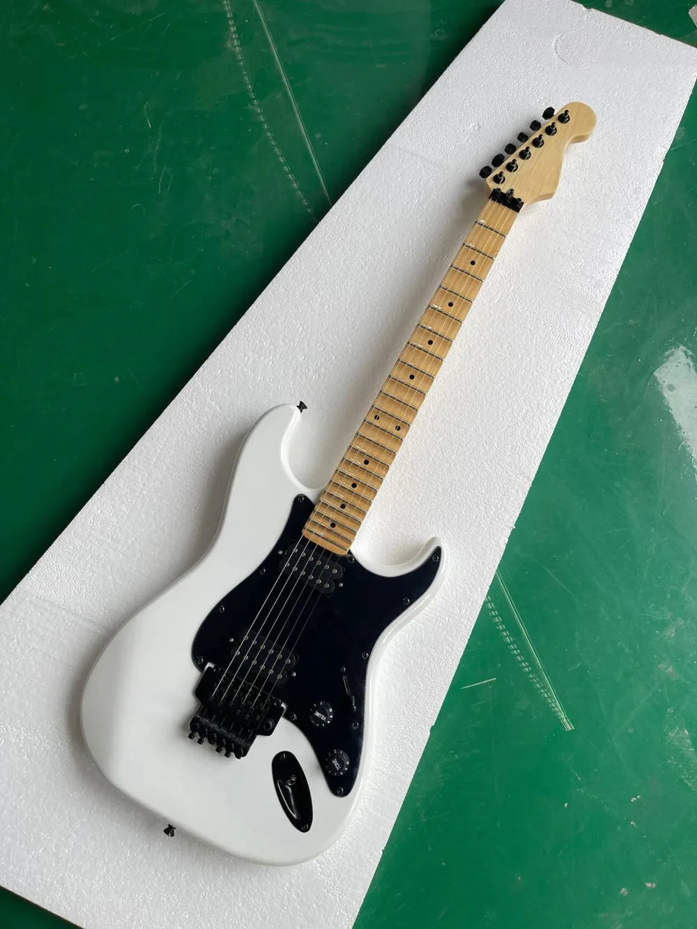 E-Gitarre mit weißem Korpus und gewelltem Ahorngriffbrett, schwarze Hardware. Bieten Sie einen individuellen Service Image