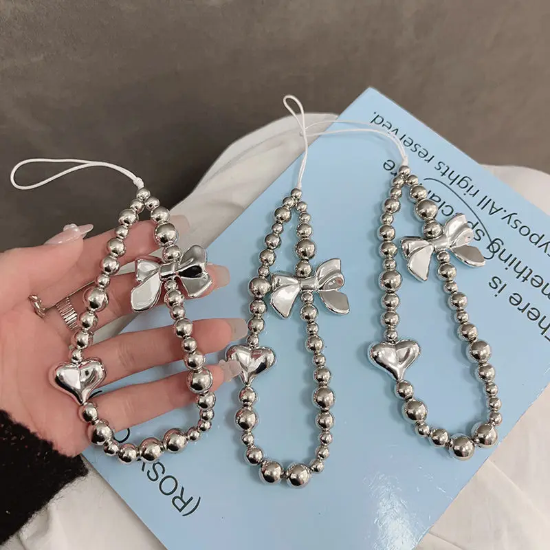 Modische, süße, silberfarbene, galvanisierte Perlen-Handykette mit Herz-Schleifen-Anhängern, Handgelenkschlaufe, Lanyard-Zubehör für iPhone- und Samsung-Hüllen Image