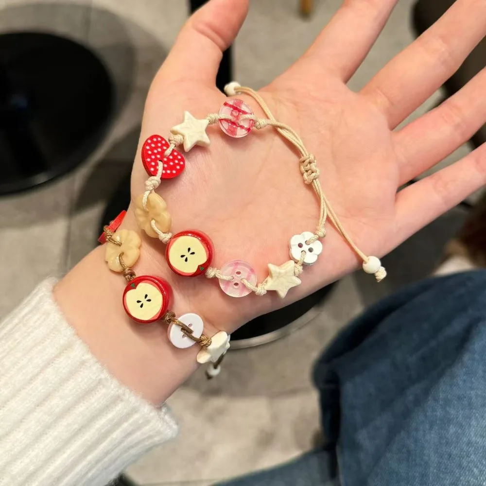 Hübsches Apfel-Charm-Armband für Mädchen mit brauner Kordel. Lustiges und stilvolles Accessoire für trendigen Damen-Modeschmuck. Neu Image